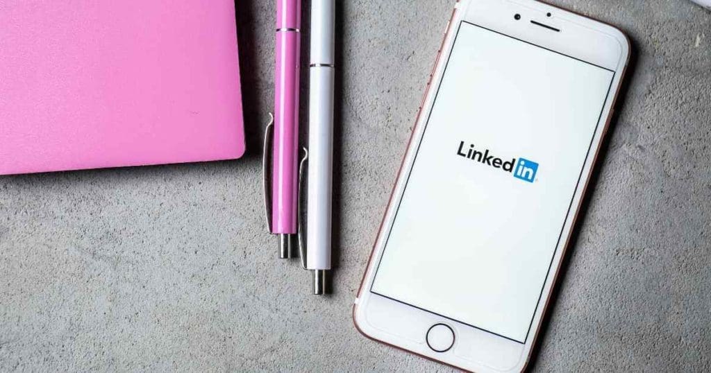 LinkedIn app running on a phone with pens and tablet on the side